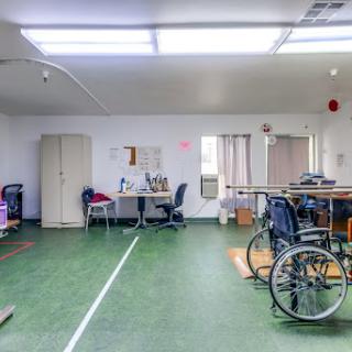 A spacious healthcare room equipped with wheelchairs and office furniture.