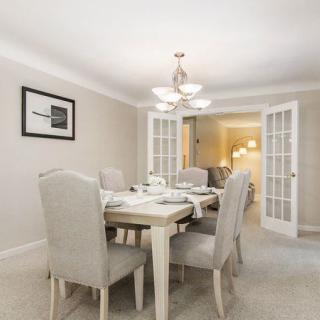 A modern and elegant dining room with a stylish chandelier and a neatly set table, featuring neutral tones.