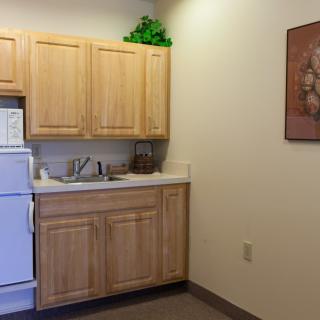 A small kitchen area with wooden cabinets, a sink, and a refrigerator.