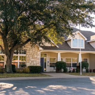A picturesque suburban house with a large tree in the front yard.