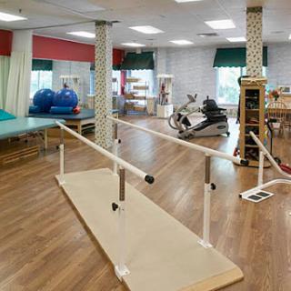 A well-equipped physical therapy studio featuring a barre for rehabilitation exercises.