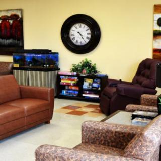 A cozy waiting room with comfortable seating, a large wall clock, and a fish tank.