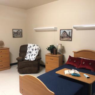 A cozy bedroom featuring a bed, a comfortable chair, and decorative elements.