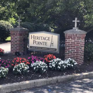 Entrance sign for Heritage Pointe surrounded by colorful flowers and brick pillars.