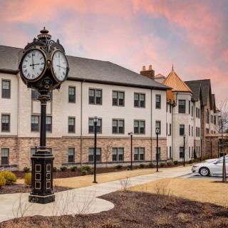 A picturesque view of a building facade with a vintage-style street clock and warm sunset skies.