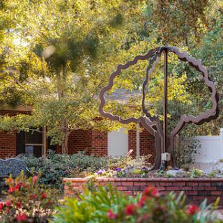 A beautifully landscaped garden featuring a tree sculpture surrounded by vibrant flowers.