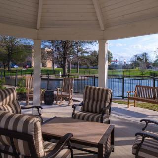 A cozy gazebo with striped patio furniture overlooking a serene lake.