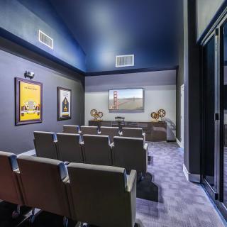 A modern home theater with comfortable seating and a large projector screen, adorned with decorative art on the walls.