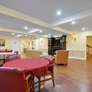 A spacious interior living room with multiple seating areas, tables, and hardwood flooring.