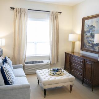 A cozy living room with a sofa, an ottoman, and stylish decor.