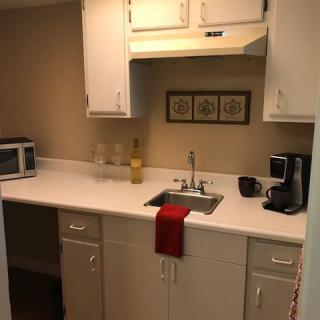 A compact kitchen with a white countertop, featuring a microwave, coffee maker, and decorative wall art.