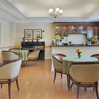 A cozy dining area with a piano and kitchen, featuring elegant seating and vibrant decor.