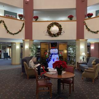 A festive lobby decorated for the holidays with a large wreath and poinsettias.