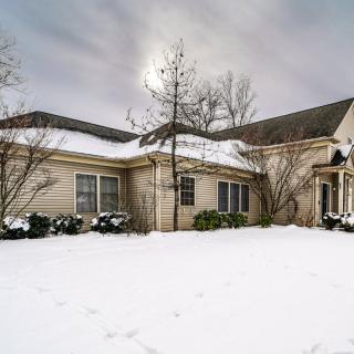 A residential house surrounded by a snowy landscape under an overcast sky.