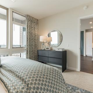 A beautifully designed modern bedroom with large windows, stylish curtains, and elegant furnishings.
