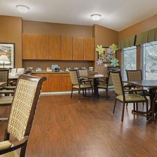 A cozy dining room with wooden flooring and neatly arranged tables and chairs.