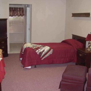 A cozy bedroom with a single bed and red bedding, featuring traditional furniture and decor.