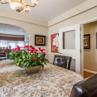 A beautifully decorated dining room featuring a floral centerpiece, elegant chandelier, and tasteful artwork.