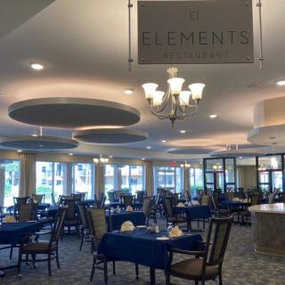 A spacious restaurant interior with elegantly set tables and modern chandeliers.