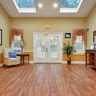 A bright lobby with comfortable seating, wood flooring, and ample natural light from skylights.