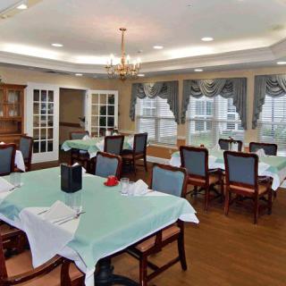 A cozy dining area with neatly arranged tables and chairs, adorned with a chandelier overhead.