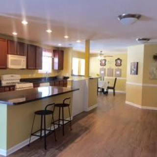 An open-concept kitchen and dining area featuring modern wood flooring, recessed lighting, and bar seating.