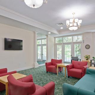 A cozy lounge area featuring red chairs and a television, illuminated by natural light.