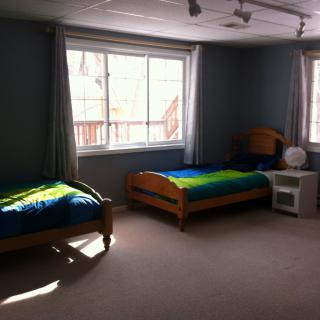 A sunlit bedroom with twin beds and large windows.