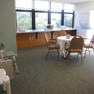 A break room with a table and chairs, featuring a small kitchenette area.