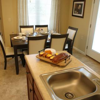 A cozy kitchen and dining area with a countertop, sink, and a neatly set dining table.