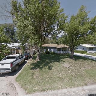 A suburban house with a grassy front yard and a pickup truck parked in the driveway.