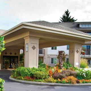 Main entrance of a building surrounded by landscaped gardens.
