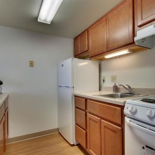 A compact kitchen with wooden cabinets, a stove, and a refrigerator.