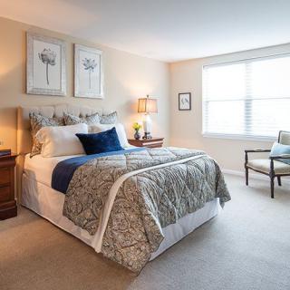 A cozy bedroom with a neatly made bed, decorative pillows, and two lamps providing warm lighting.