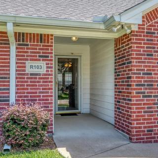 A house entrance with a brick exterior and a covered path leading to the front door.