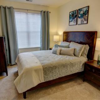A cozy bedroom featuring a neatly made bed, wooden furniture, and soft lighting.