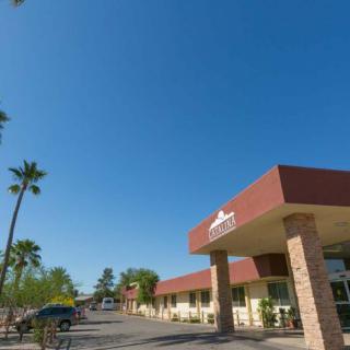 A motel with palm trees and a clear sky, featuring a parking lot in front.