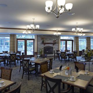 A spacious dining room with elegant chandeliers and neatly arranged tables and chairs.