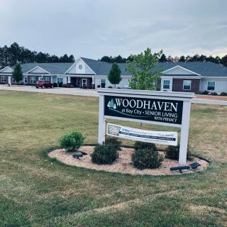 A sign for Woodhaven, in front of residential buildings under a cloudy sky.