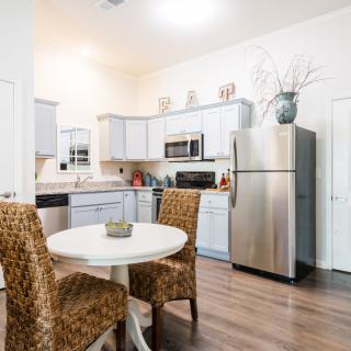 A modern kitchen and dining area with a round table, upholstered chairs, and stainless steel appliances.