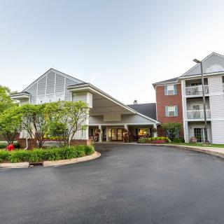 A view of a building entrance with a landscaped driveway and surrounding greenery.