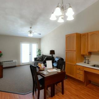 An open-concept living and dining area with a kitchenette, featuring wood flooring and modern furniture.