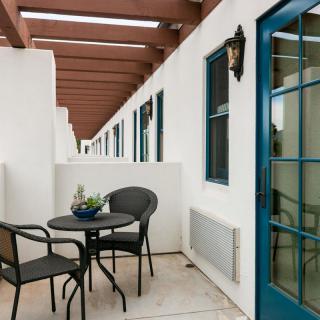 A modern patio with a small table and chairs, accented by a blue door.