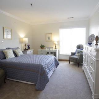 A bright and cozy bedroom with a neatly made bed, elegant furniture, and soft lighting.