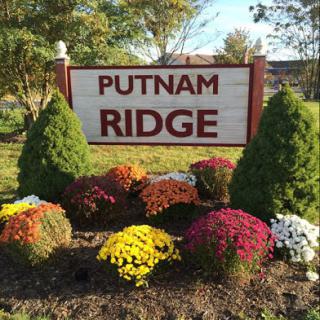 Welcoming sign for Putnam Ridge surrounded by vibrant flowers.