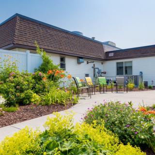 A well-designed garden patio area with chairs surrounded by vibrant flowers and landscaping.