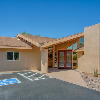 A modern house with a large entrance, set in a desert landscape under a clear blue sky.