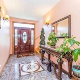 A beautifully designed foyer with a wooden entrance door, decorative table, and potted plants.