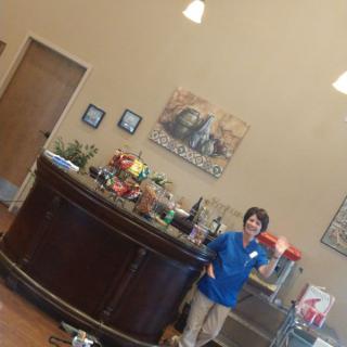 A person stands behind a reception desk decorated with balloons in an office setting.