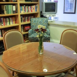 A cozy reading area with a round table and flowers in a library setting.